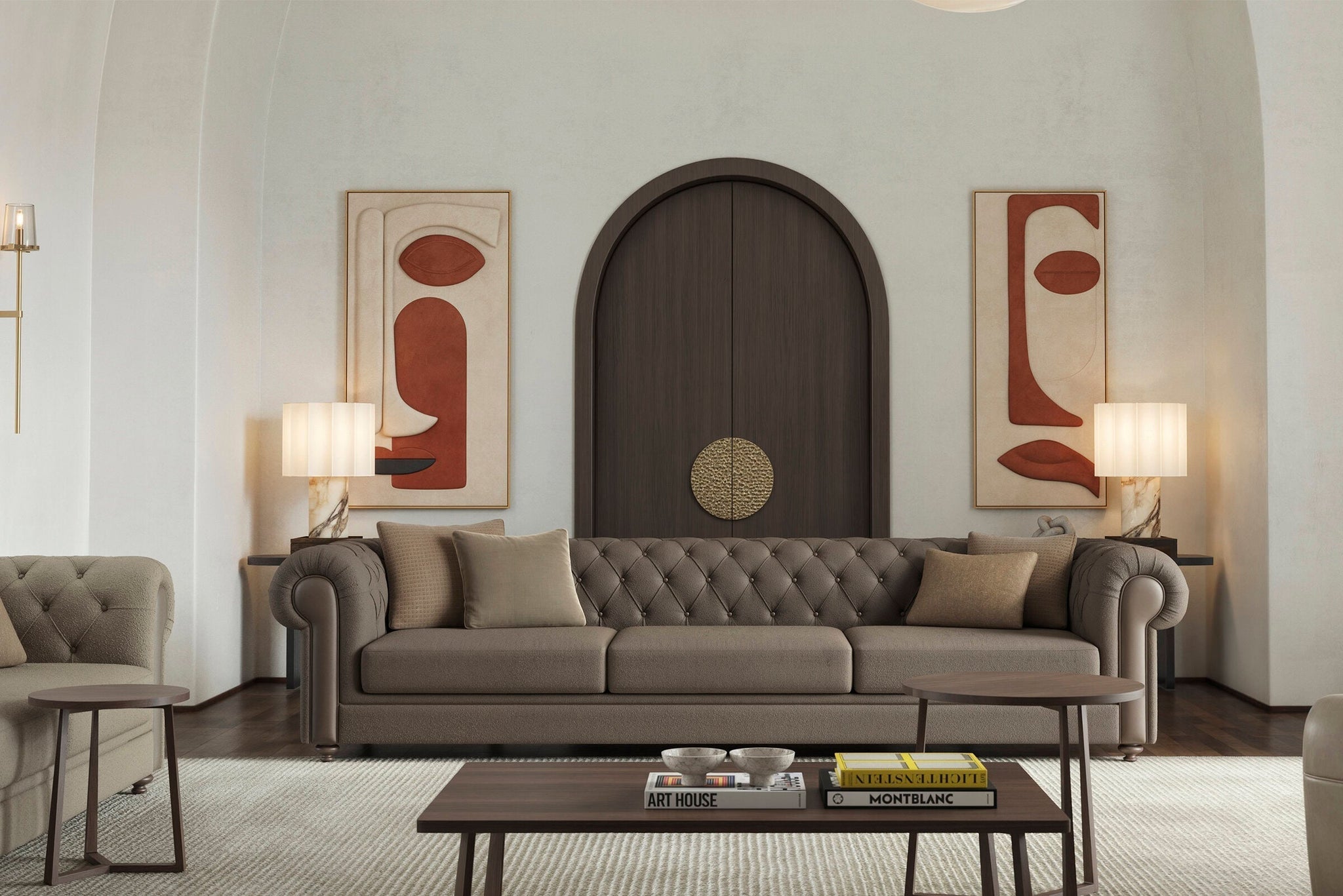 Elegant living room with a tufted brown Chesterfield sofa, wooden coffee table with books and decor, two armchairs, table lamps, and abstract art above a dark arched doorway.