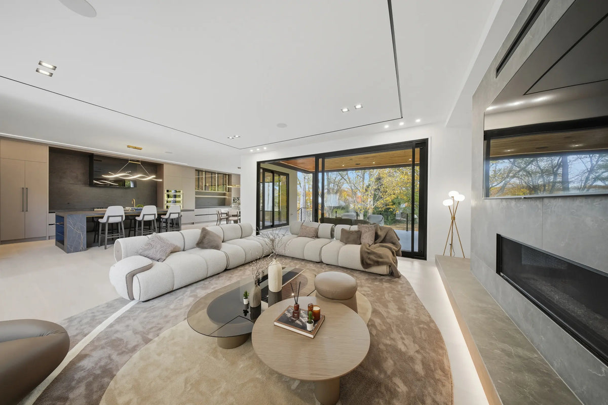 Open-concept living room with curved sectional sofa, fireplace, and floor-to-ceiling windows.